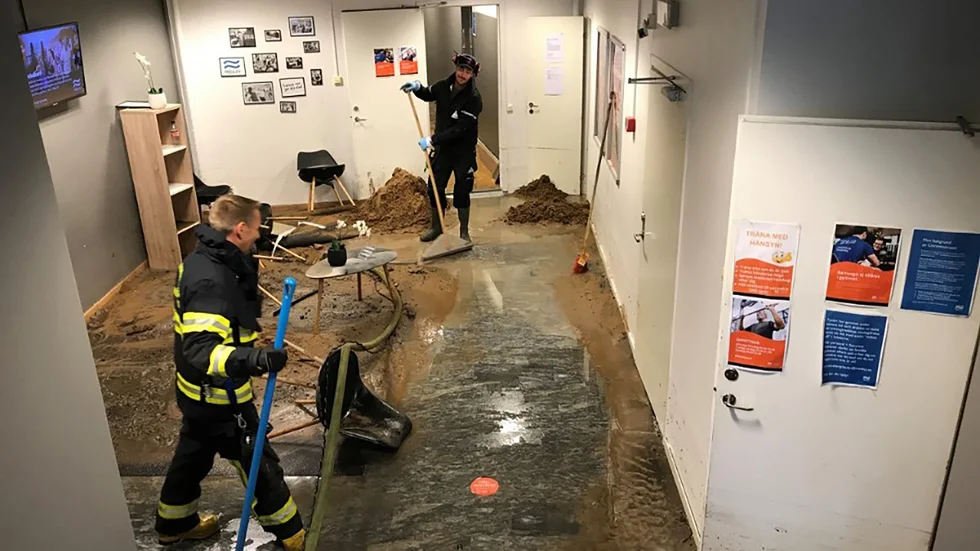 Martin Norén och Björn Ahlin hjälps åt att få undan vattenmassorna som forsat in i gymmet.