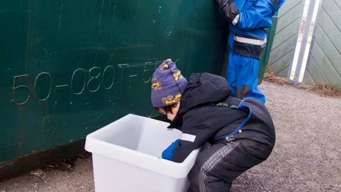 Emil Roslund sträcker på sig för att nå upp till hålet på återvinningen. Han får hjälp av Jordan Thorsén att tömma det sista i lådan för plast.