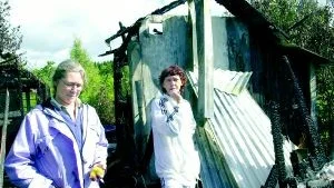 Gunnel Astridsdotter och Solvig Singer står vid resterna av de nedbrunna stugorna på Berga kolonilottsområde. Gunnels hus är helt förstört medan Solvigs klarat sig undan med en skadad veranda.
FOTO: JANNE FORSBY