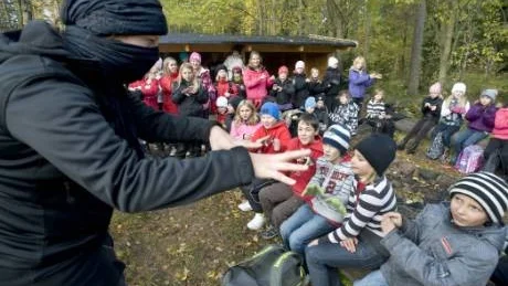 En av Jurslaskolans lärare försöker lära eleverna en sång från det främmande landet TadzMbekistan. Det är svårt att se vem läraren är, bakom det dolda ansiktet...