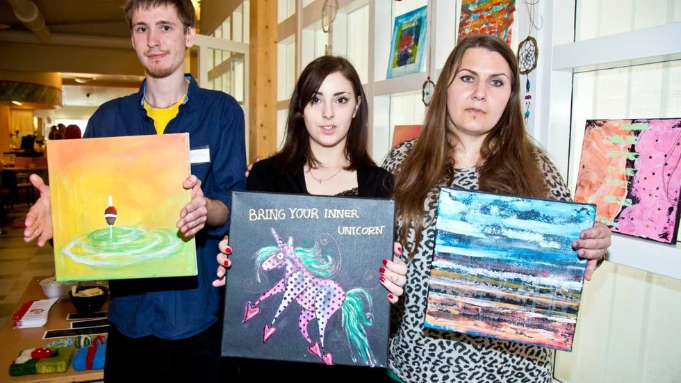 André Lindberg, Sara Marklund och Mandy Lidberg visar några av tavlorna som konstelever gjort och som fanns att köpa när det var Folkhögskolans dag på Framnäs.