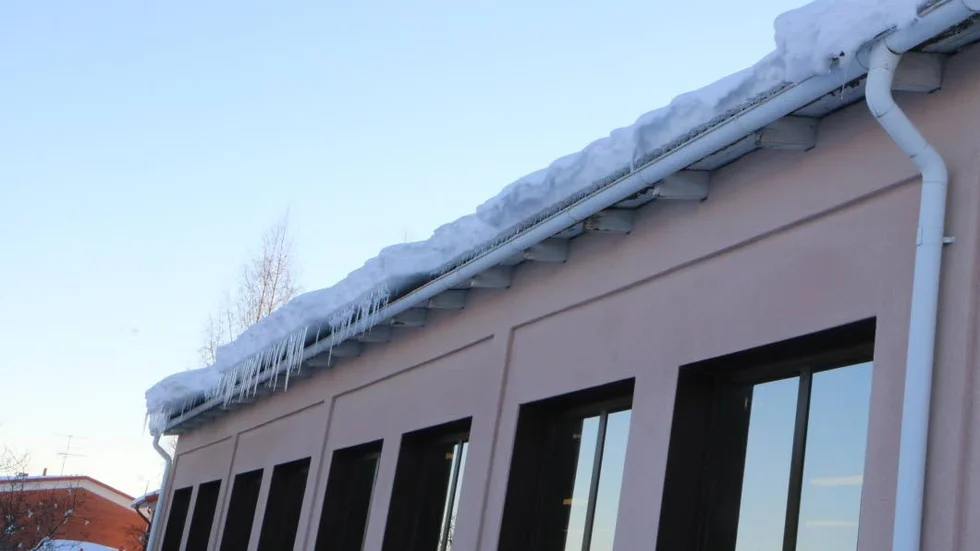 Mängder av snö har fastnat på taket och bildat drivor som hänger ut över kanten där det också bildats stora istappar.
