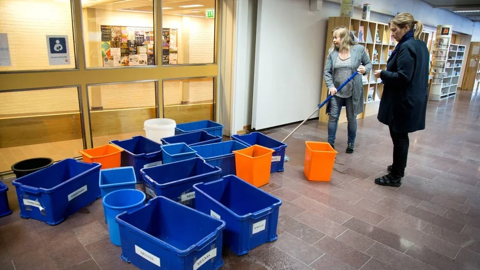 Marianne Jonsson och Kristina Englund har fullt upp med att torka golvet i biblioteket.