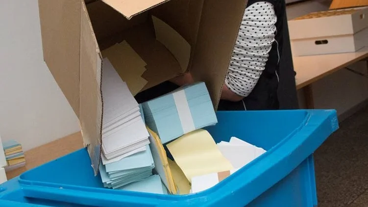 Lotta Åman, valnämndens ordförande, städar bort överblivna röstsedlar.