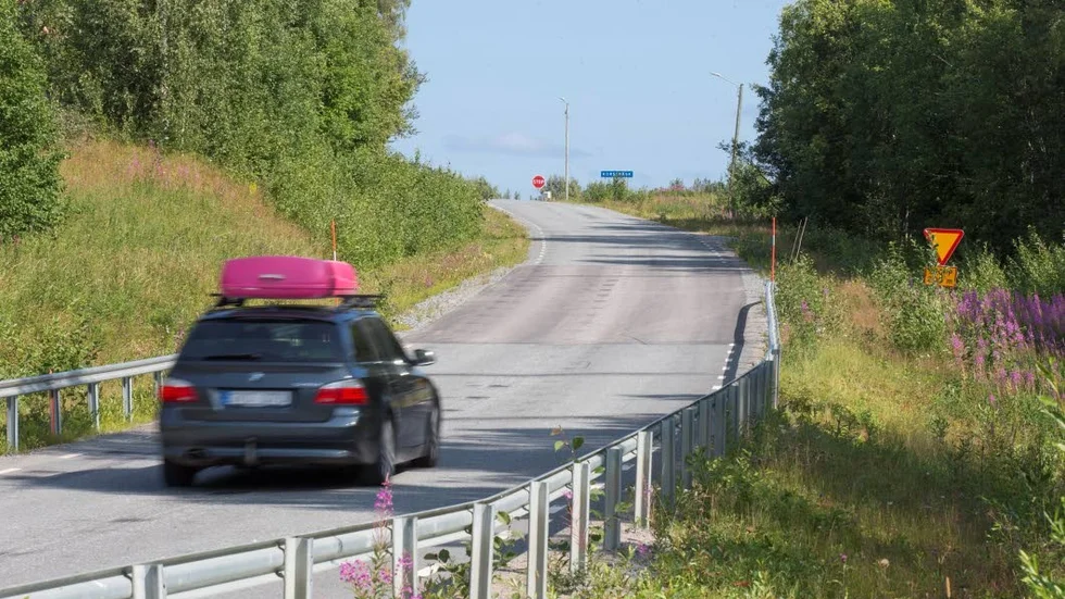 En skylt varnar för att det kommer en korsning men den är delvis dold bland buskaget.