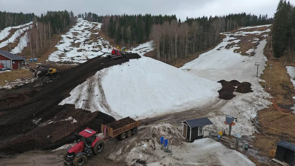I Tolvmannabacken i Kisa pågår arbetet för fullt. En 40 000 kubikmeter stor snöhög håller just nu på att täckas med flis inför heta sommardagar.