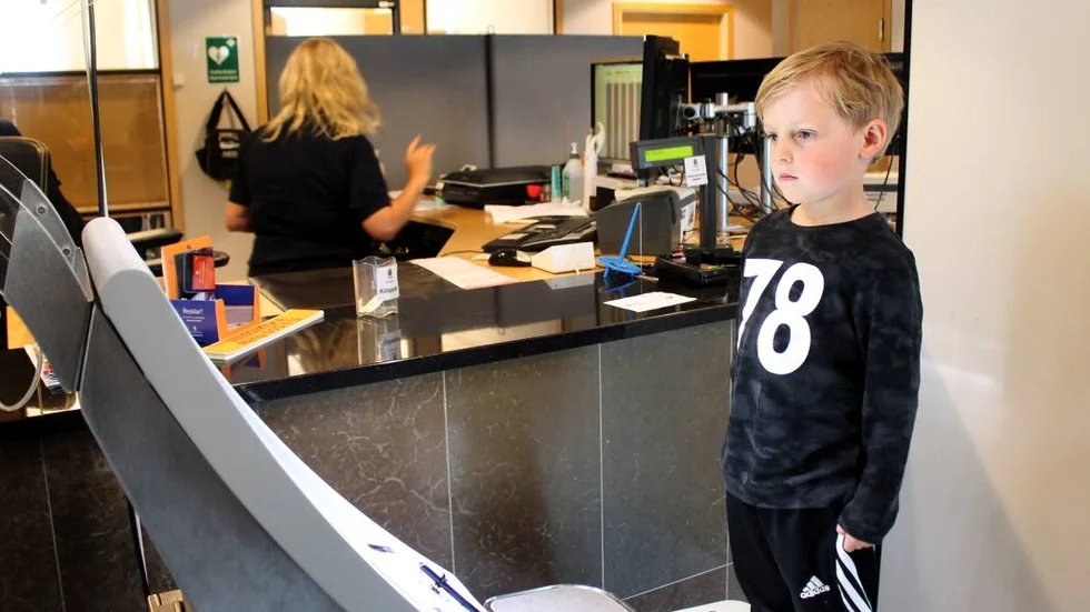 Fyraårige Oliver Mellberg gör sig redo för att bli fotograferad. Passhandläggare Kaija Eriksson sköter det tekniska.