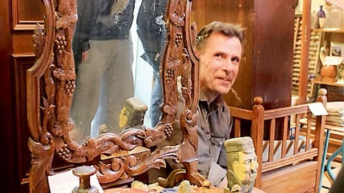 Hans Lennartsson samtalar med en kund om en möbel i teak. Bredvid står en ankarledsspegel, ett riktigt fint hantverk av en bildhuggare.