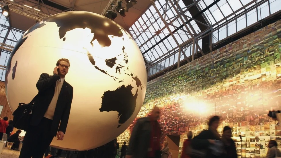 File - In this Tuesday Dec. 15, 2009 file photo, a man speaks on his cell phone in front of a giant globe in Copenhagen. The European Union on Tuesday, June 30, 2015 agreed to end mobile roaming charges within two years and allow travelers to pay the same price for calls, text messages and data anywhere in the 28 EU nations. (AP Photo/Virginia Mayo, File)