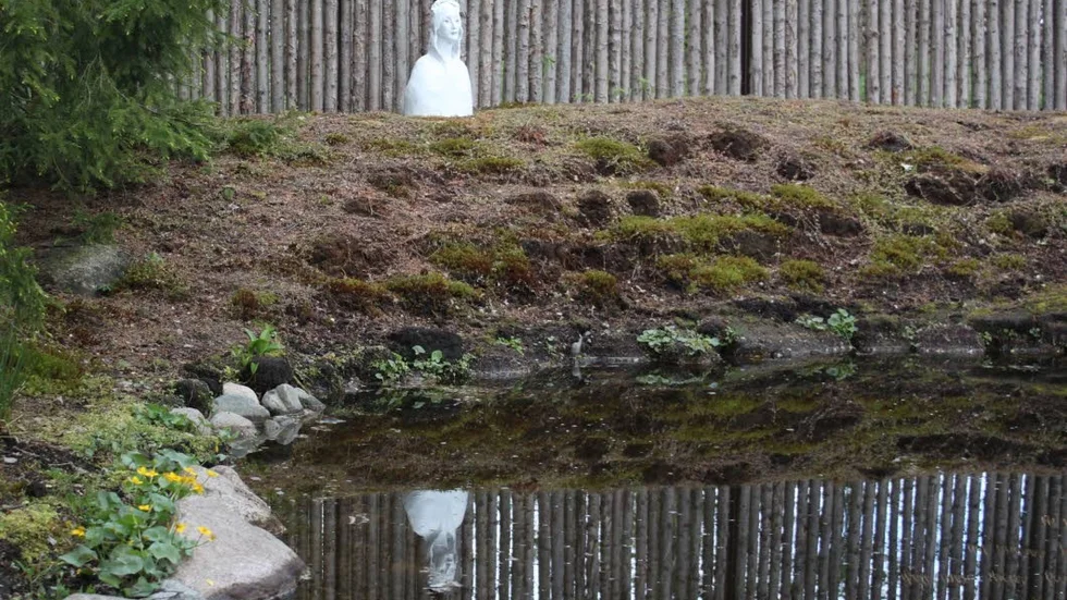 Karin Wibergs skulptur Helgonet blickar ut över tjärnen.