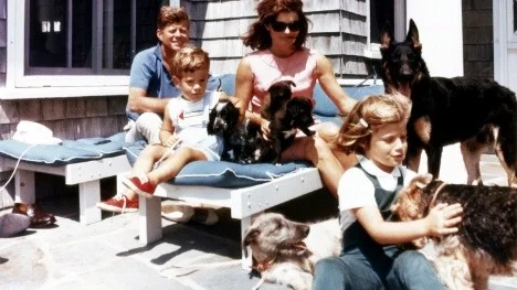 14 Aug 1963. Familjen Kennedy, John och Jackie med barnen John Jr och Caroline, på terassen till huset på Squaw Island i Hyannisport, Massachusetts, med många hundar och valpar.