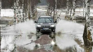 Snön smälter och här och där bildas stora vattensamlingar.Sund heter platsen nära Alunda där bilen forsar fram