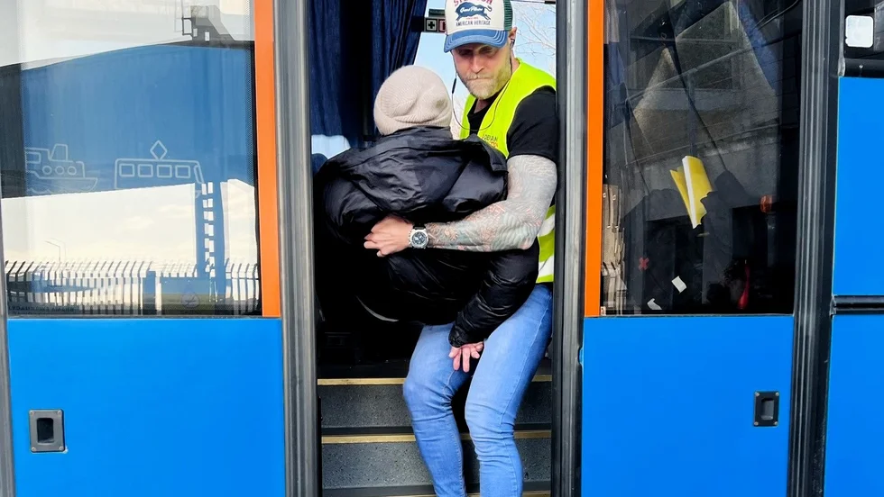 Christian Mårtensson hjälper en rullstolsburen äldre man upp i bussen.