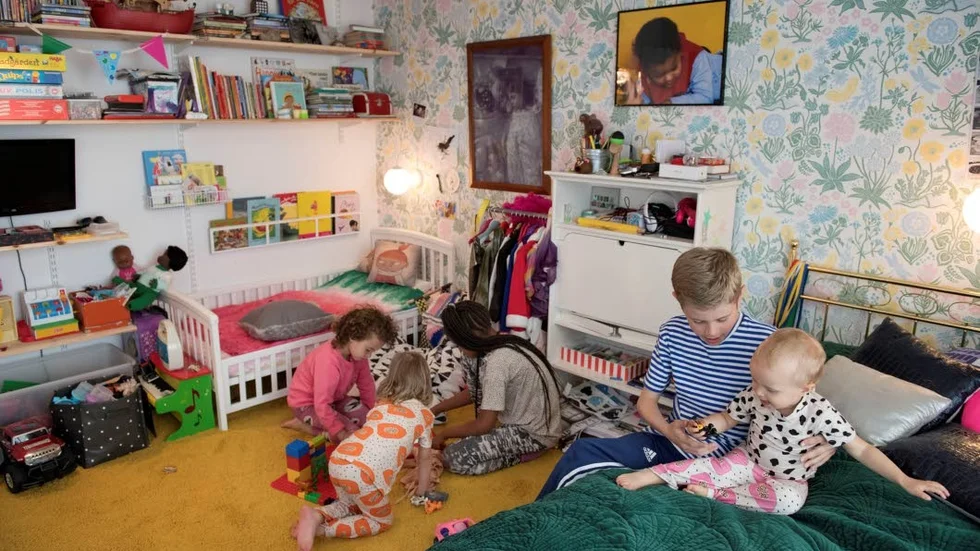 Barnrum. Rio, Ali och Billie leker på golvet i barnrummet. I sängen sitter Folke med Neneh.