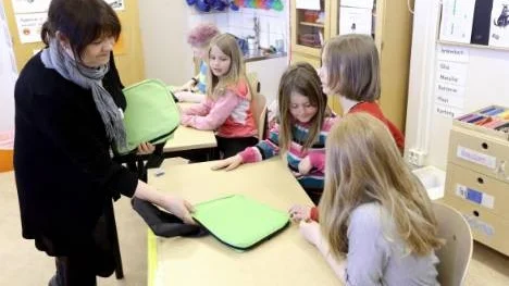 Läraren Lena Gabrielsson Renberg delar ut de gröna väskorna med majblommor till föväntansfulla barn i klass 2 i Jävreskola.
