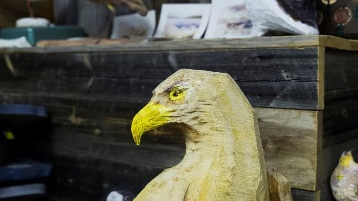 Skarpögd. En rovfågel i trä spanar nyfiket på sin omgivning.