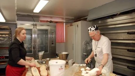 FULL FART. Under morgontimmarna när brödet produceras är det hög aktivitet i bageriet. Helena Eriksson tar hand om nygräddat bröd och Ingemar Holmström gör bakelser.