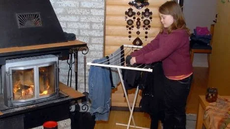 Lois hänger tvätt intill öppenspisen i det  kombinerade köket/vardagsrummet.
