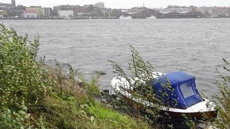 STRANDSATT BÅT. Den här båten hade slitit sig i den hårda vinden. Den drev till sist mot banken mellan Norra Hamn och badhuset i Luleå. Räddningstjänsten kunde inte dra loss båten eftersom den då riskerade att springa läck och sjunka. Foto: Roland S Lundström