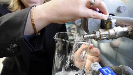 ÄNTLIGEN. Efter två års arbete med vattenledningen kan Lenita Ericson äntligen tappa de första dropparna direkt från ledningen i Bensbyns vattenverk.