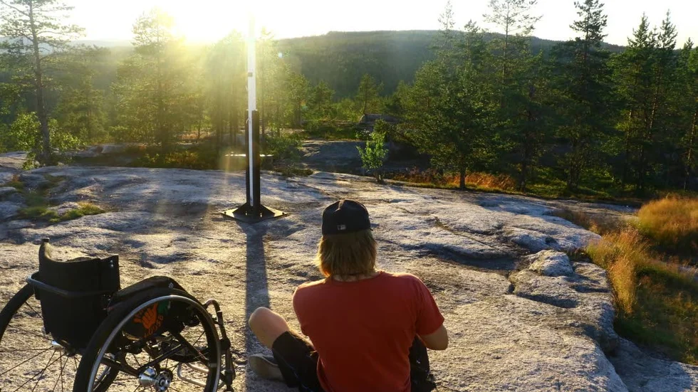 Luppioberget. Sebastian Westin bestiger berg i rullstol. Här njuter han av den vackra solnedgången i Tornedalen.