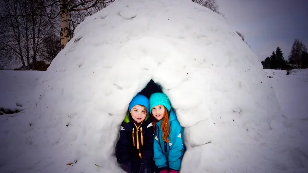 John och Olivia Nyberg tycker om sin snöskapelse, som rymmer alla 14 barn som byggt den.