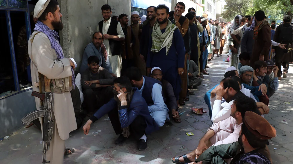 En taliban bevakar en kö framför en bank i den afghanska huvudstaden.
