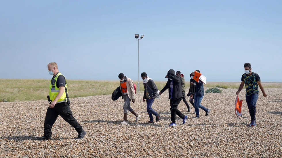 Polis eskorterar en grupp människor som tros ha anlänt sjövägen till Dungeness i södra England.