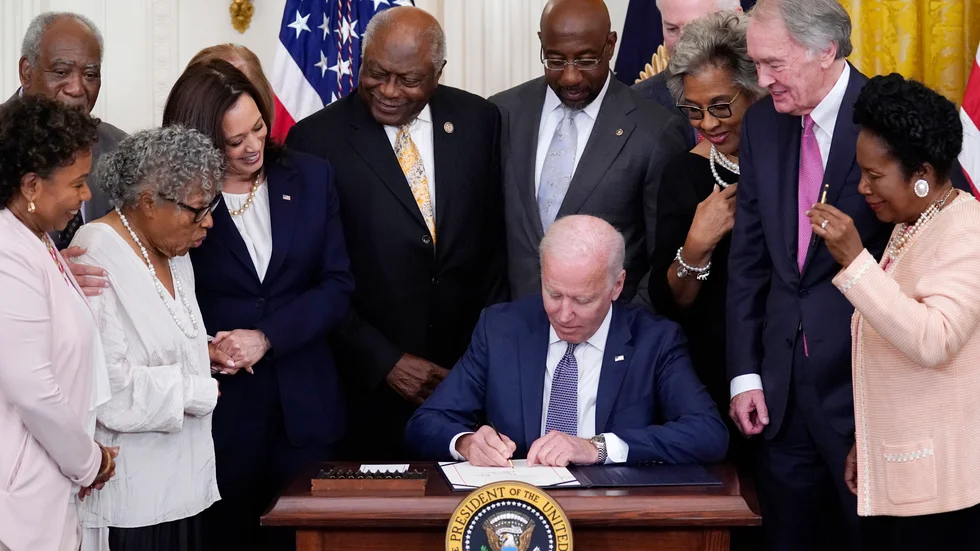 President Joe Biden skriver under lag om att göra 19 juni till nationaldag. Han omgärdas av kongressledamöter.
