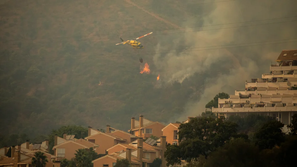 En helikopter vattenbombar branden i Estepona, Spanien.