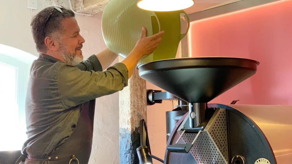Michael Isaksson, som äger Rosteriet Vadstena, laddar kaffemaskinen med bönor.