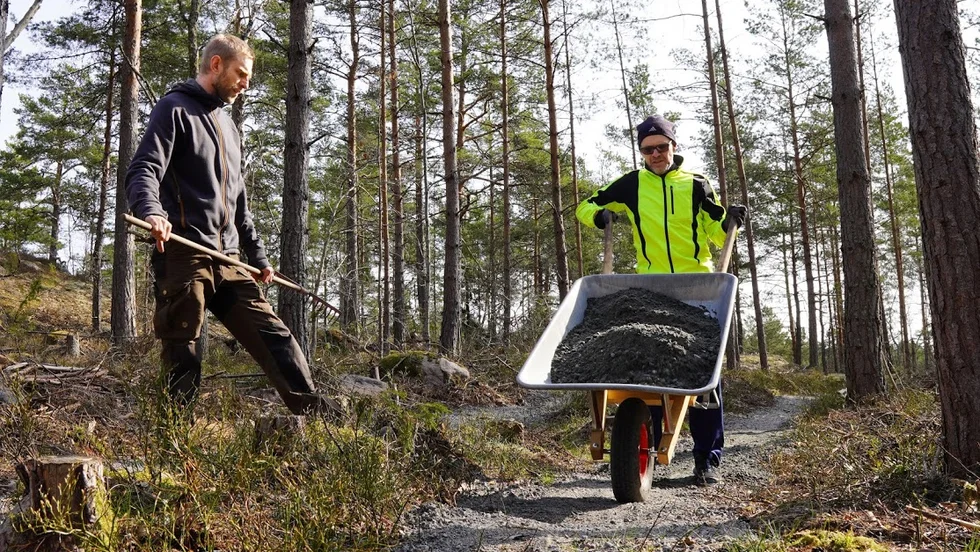Torbjörn Iserstål, gul jacka, och Fredrik Berg Dunge lägger på ett lager med grus på det nya MTB-spåret.