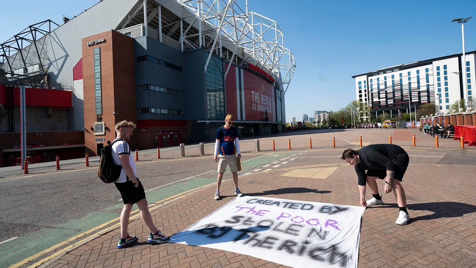 Supportrar utanför Manchester Uniteds hemmaarena Old Trafford lägger ut en banderoll som protesterar mot planerna på en superliga.