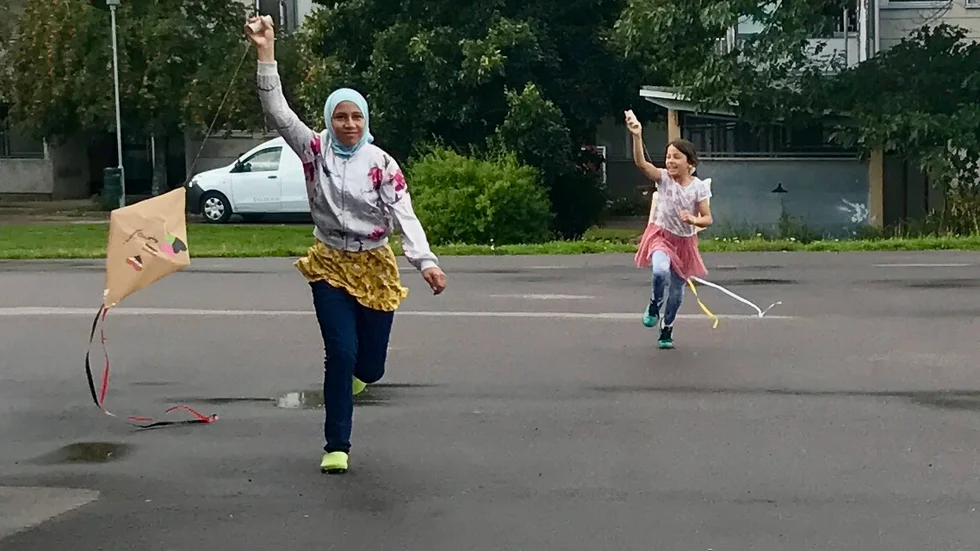 Syskonen Nooralhoda och Lana-Lina Taha springer glatt runt runt med sina drakar på skolgården.