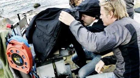 Fotografen Calle Persson och regissören Erik Leijonborg får ta ett svart skynke till hjälp för att kunna se bilderna på monitorn i solskenet.