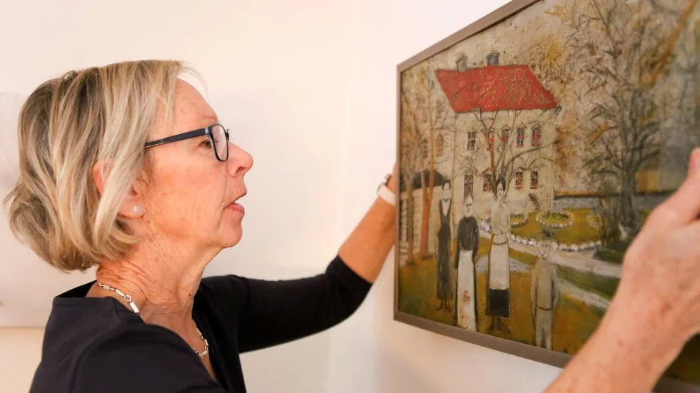 GÅRDSBILD. Bodil af Petersens visar en målning på plåt  av gården gjord av konstnären Oskar Högberg.