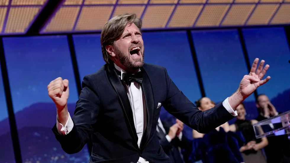 Ruben Östlund jublar sedan han tilldelats ytterligare en Guldpalm för "Triangle of sadness".
