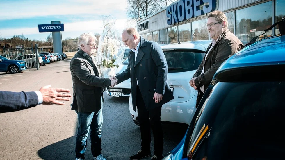 Handslag och blommor utdelas mellan Jan-Erik Larsson (S) och Alexander Forss när de nya elbilarna hämtades ut under måndagen. Till höger i bild syns kommunjuristen Niklas Witt.