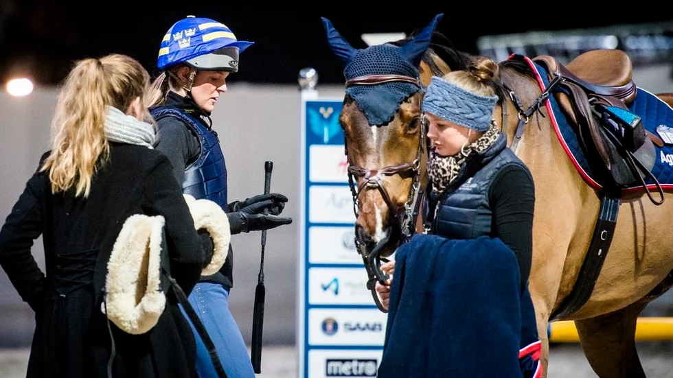 Anna Freskgård diskuterar med sin hästskötare efter att ha provat banan inne på Friends Arena med hästen Fly Away