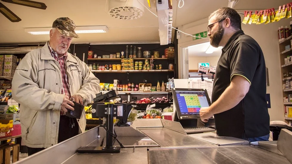 Kunden Nils-Erik Martinsson betjänas av Leif Elsberg bakom disken.