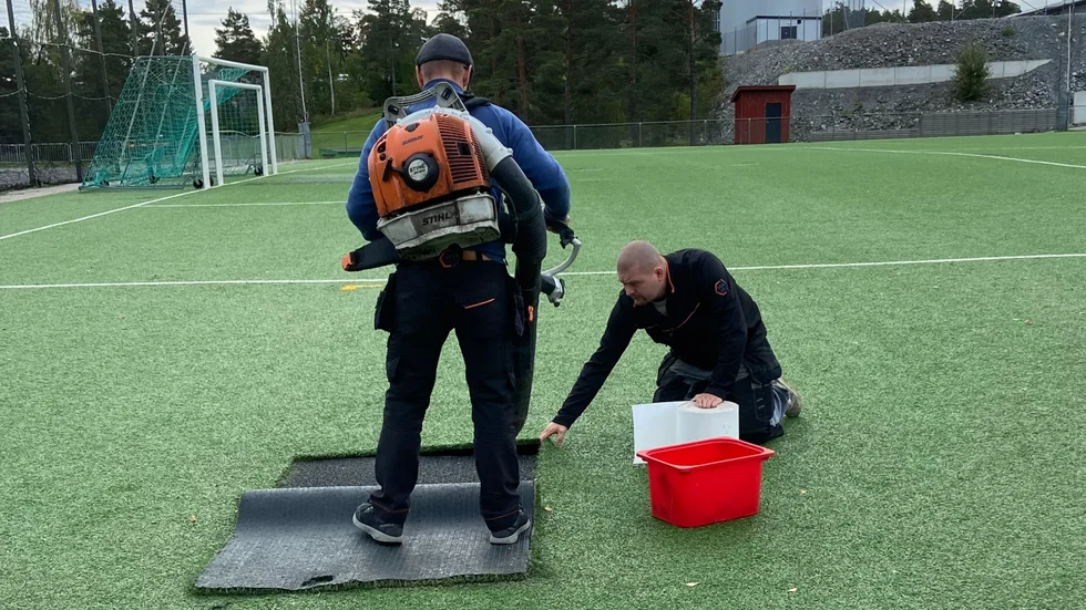 Daniel Jarestrand och Erik Tholin, idrottsplatsvaktmästare på Strängnäs kommun, skar upp mattan för att en expert på besök skulle kunna undersöka paddens standard.