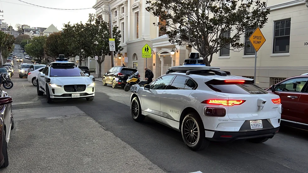 Två självkörande taxibilar tillhörande Waymo möts på en gata i San Francisco.