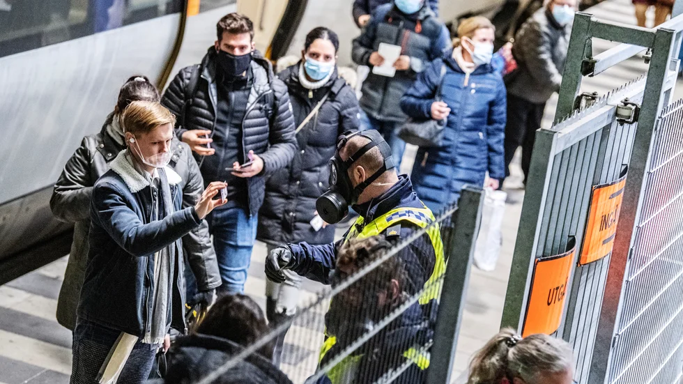 Polis i skyddsmask kontrollerar resenärer som ankommit från Danmark med Öresundståg på perrongen på Hyllie station i Malmö. Arkivbild från december 2020.