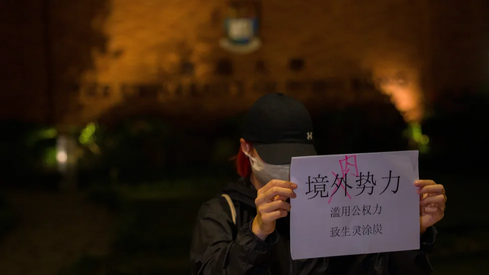 En demonstrant vid ett universitet i Hongkong håller upp ett budskap som bland annat kritiserar maktfullkomlighet hos regeringen. Bilden togs på tisdagskvällen.
