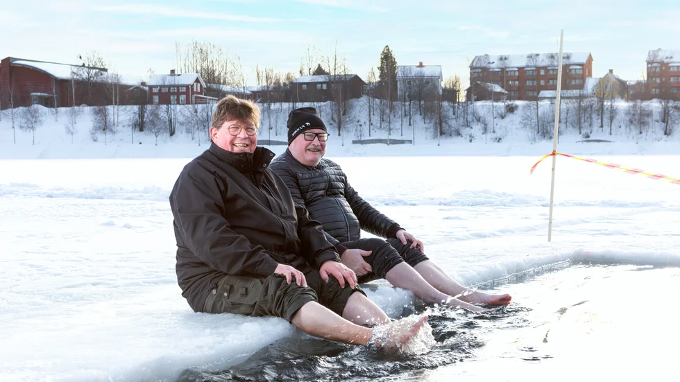 Dark & Cold Winter Swim founders, Jarkko Enqvist (left) and Lasse Westerlund (right) having a paddle in the ice hole on before the Winter Swim event in Skellefteå, 2023.