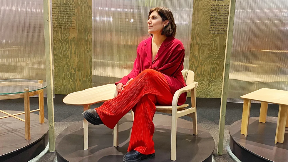 Ida Fokin ställer ut på Stockholm Furniture Fair 2023 och sitter i sin fåtölj, intill sitt bord, som hon har designat och tillverkat tillsammans med några klasskompisar på programmet för produktutveckling och möbeldesign på Jönköpings Universitet.