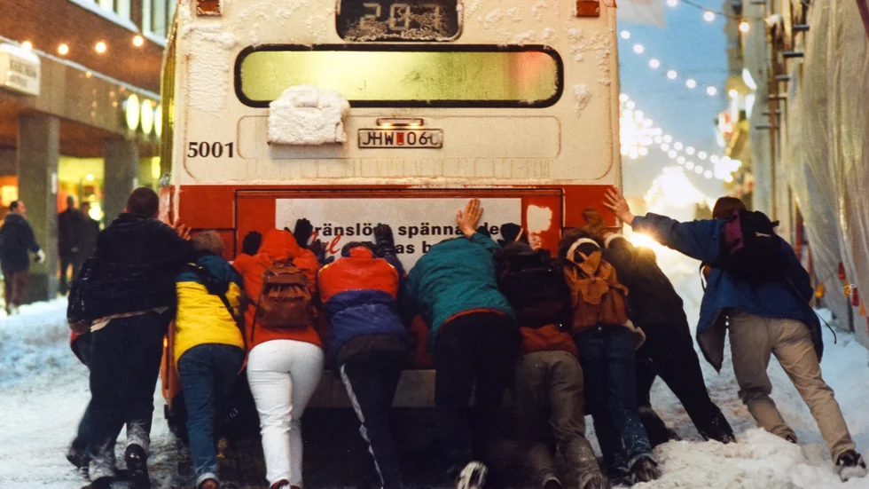 Resenärerna knuffar fram sin buss under snökaoset 1995. 