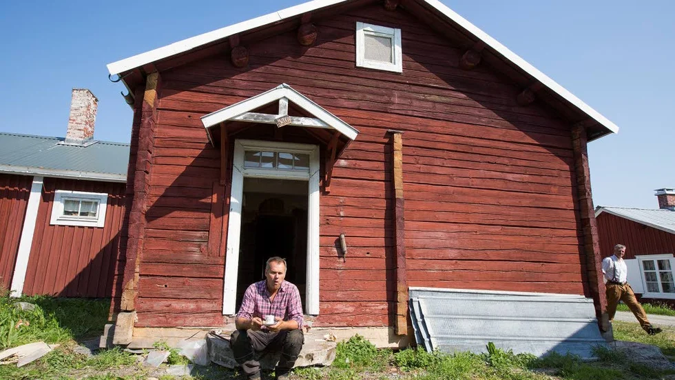KAFFEPAUS. En exteriör på kyrkstuga nummer 336 i kyrkbyn i Gammelstad. Hantverkaren Kent Westerlund unnar sig en kopp kaffe på stenbron.