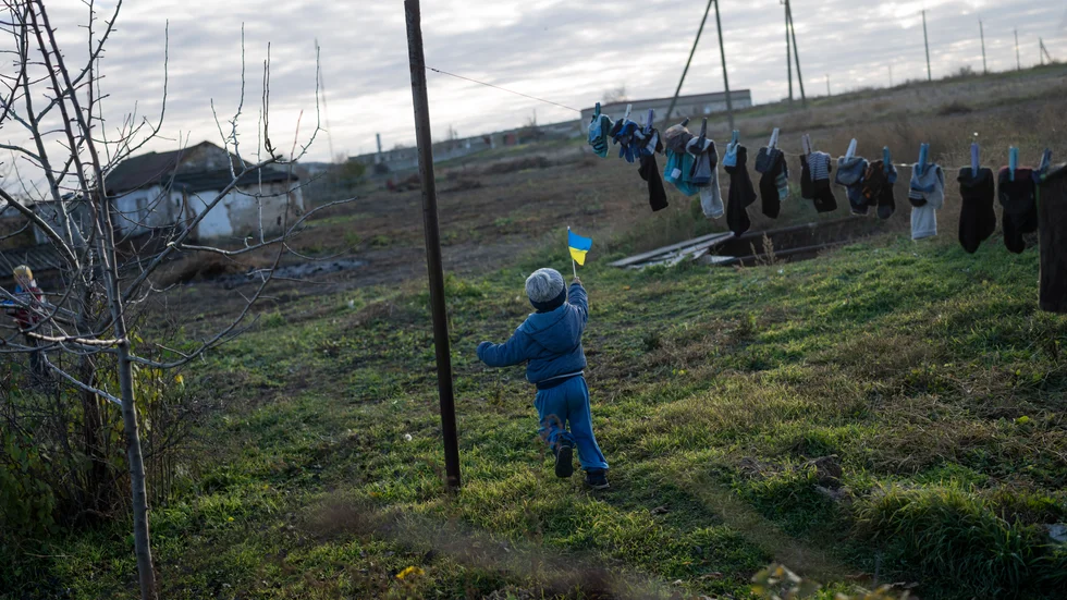 Ett barn leker med en ukrainsk flagga i utkanten av Cherson i södra Ukraina i november 2022.