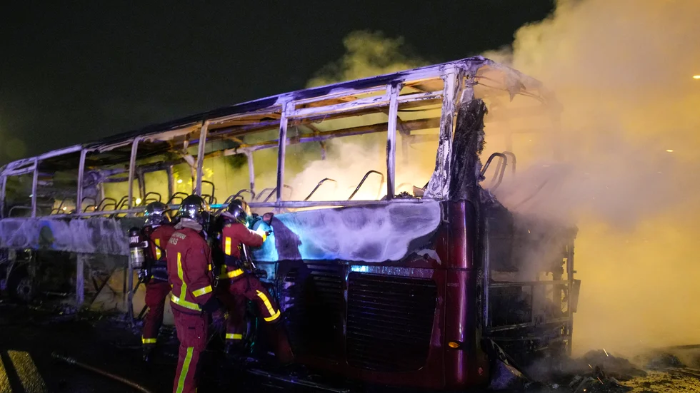 Räddningstjänsten försöker släcka en brinnande buss under natten till lördag i Parisförorten Nanterre.
